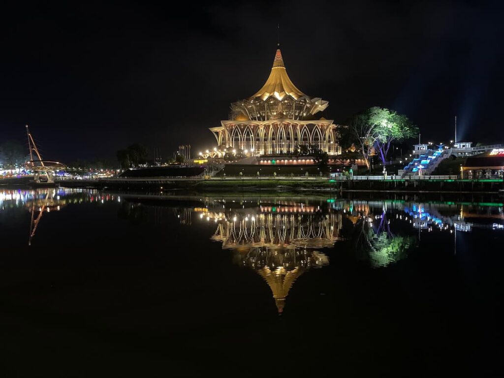 Photo State Assembly Building in Kuching at night with reflection in the water.