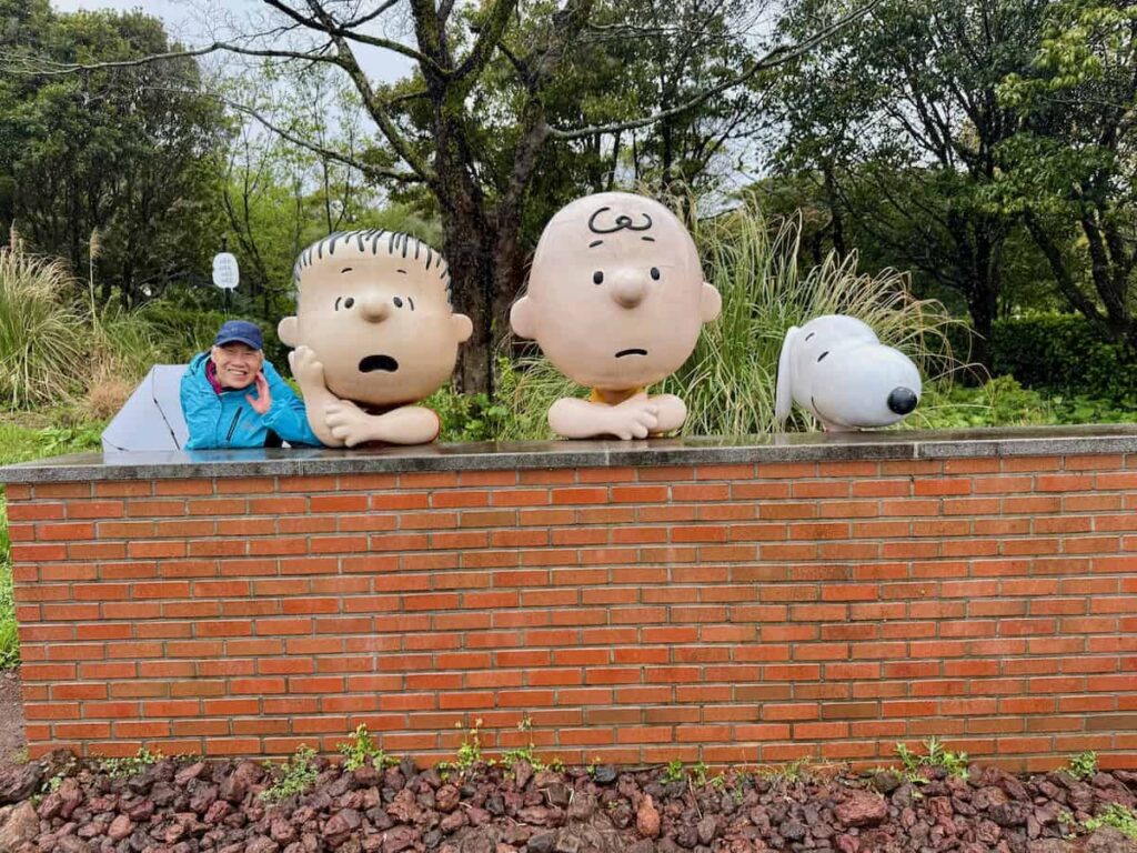 Woman standing next to Charlie Brown, Linus and Snoopy
