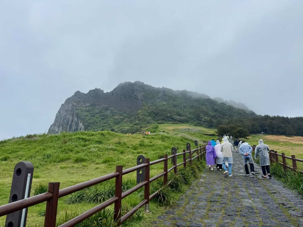 People walking in raincoats up The walk up a fog covered mountain, Jeju Island